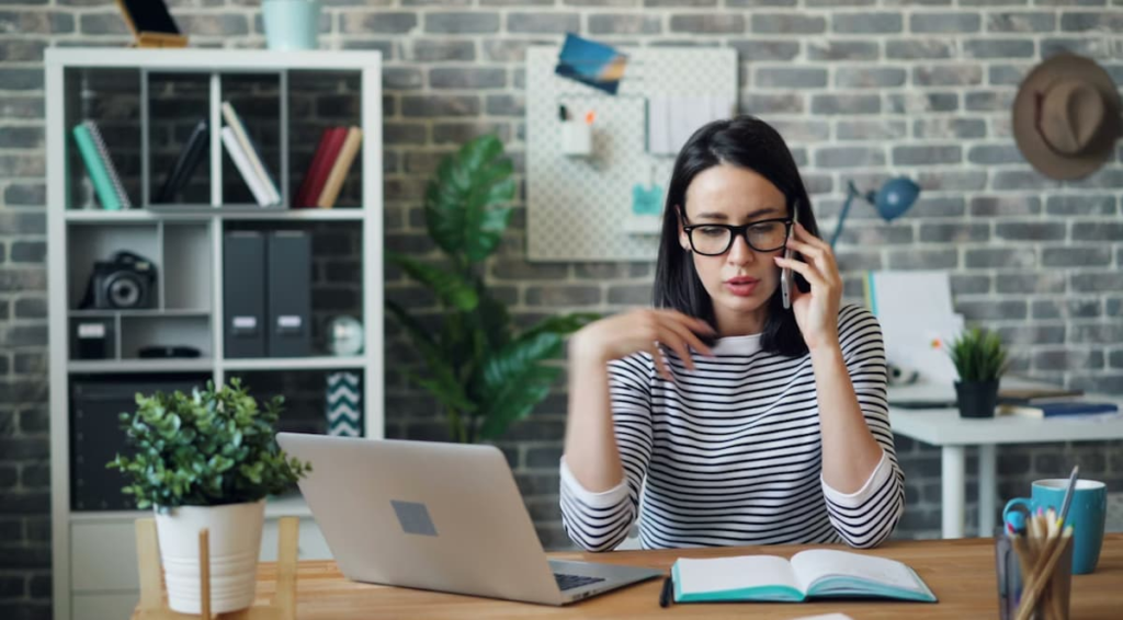 Kvinde med mobil i hånden på kontoret