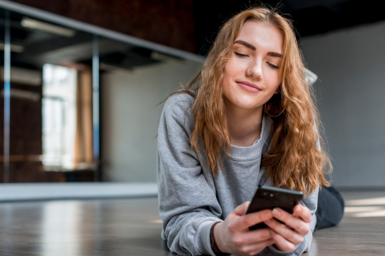 Billigste mobilabonnement til studerende - ung studerende ligger med mobilen