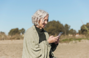 Mobilabonnement til ældre: De bedste valg i 2026 Mobilabonnement til ældre - ældre dame på strand med mobilen