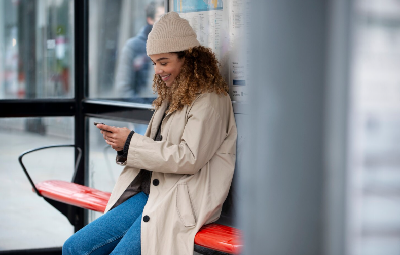 Kvinde sider og venter på sit tog - mobilabonnement til pendlere