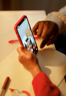 Lille barn kigger på sin røde mobiltelefon - mobilabonnement børn